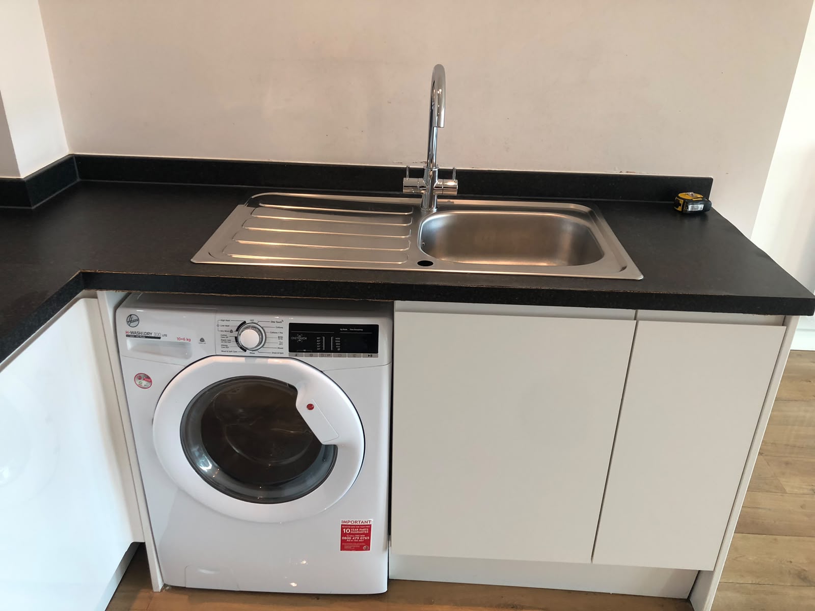Clean kitchen with stainless steel sink and utility area
