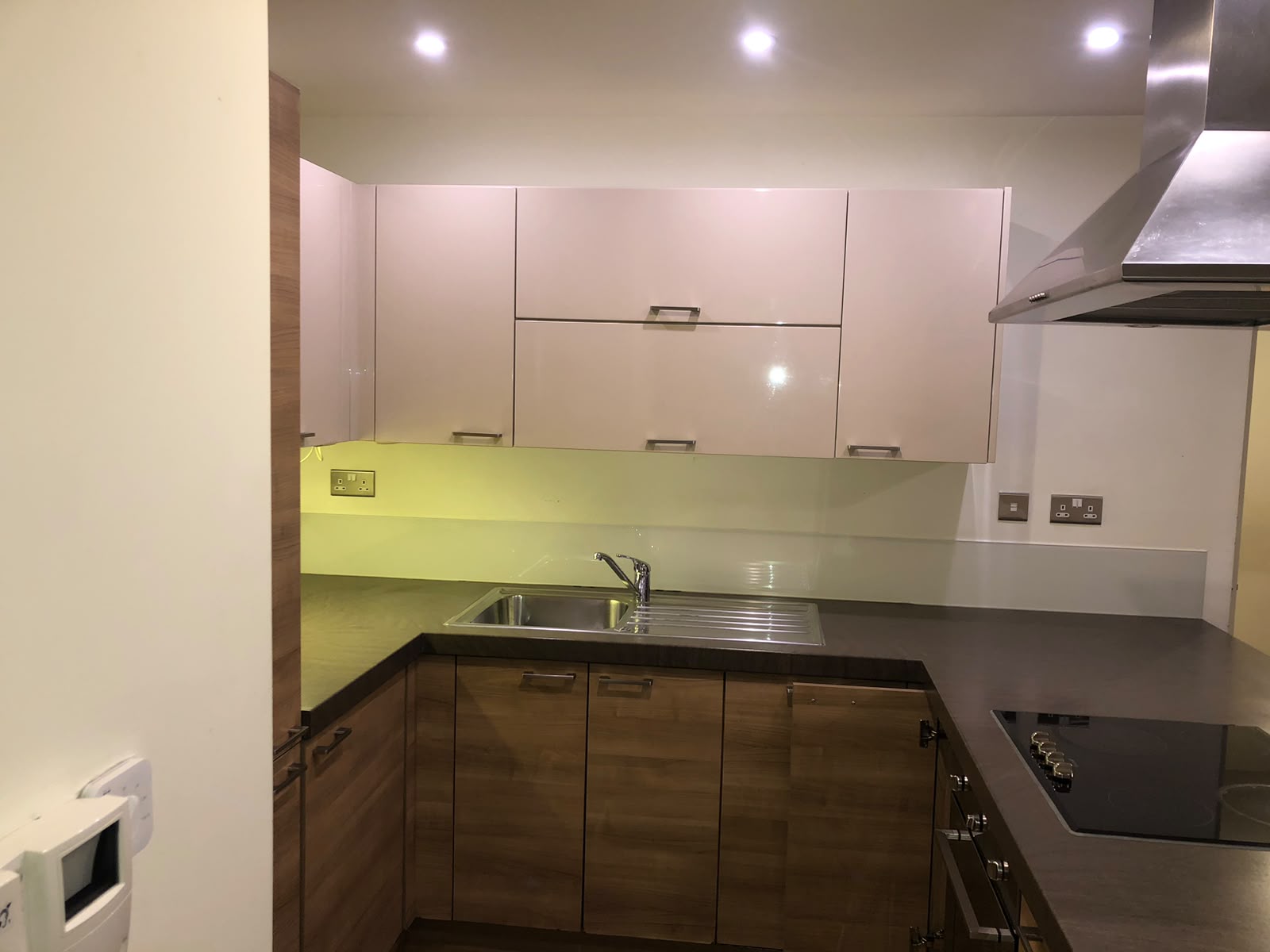 Clean wood and gloss kitchen with green splashback